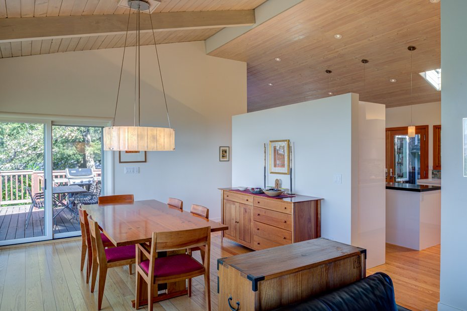 Dining area with wood table and chairs beneath a pendant light, opening directly to an outdoor deck through sliding glass doors.