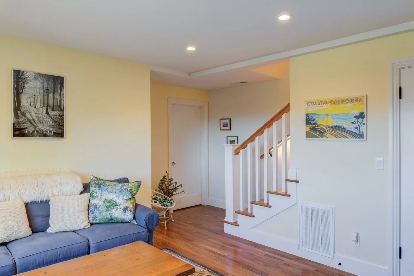 Main level living area with the renovated stair and railing, warm wood floors, and recessed lighting that ties the refreshed rooms together after the whole house updates.