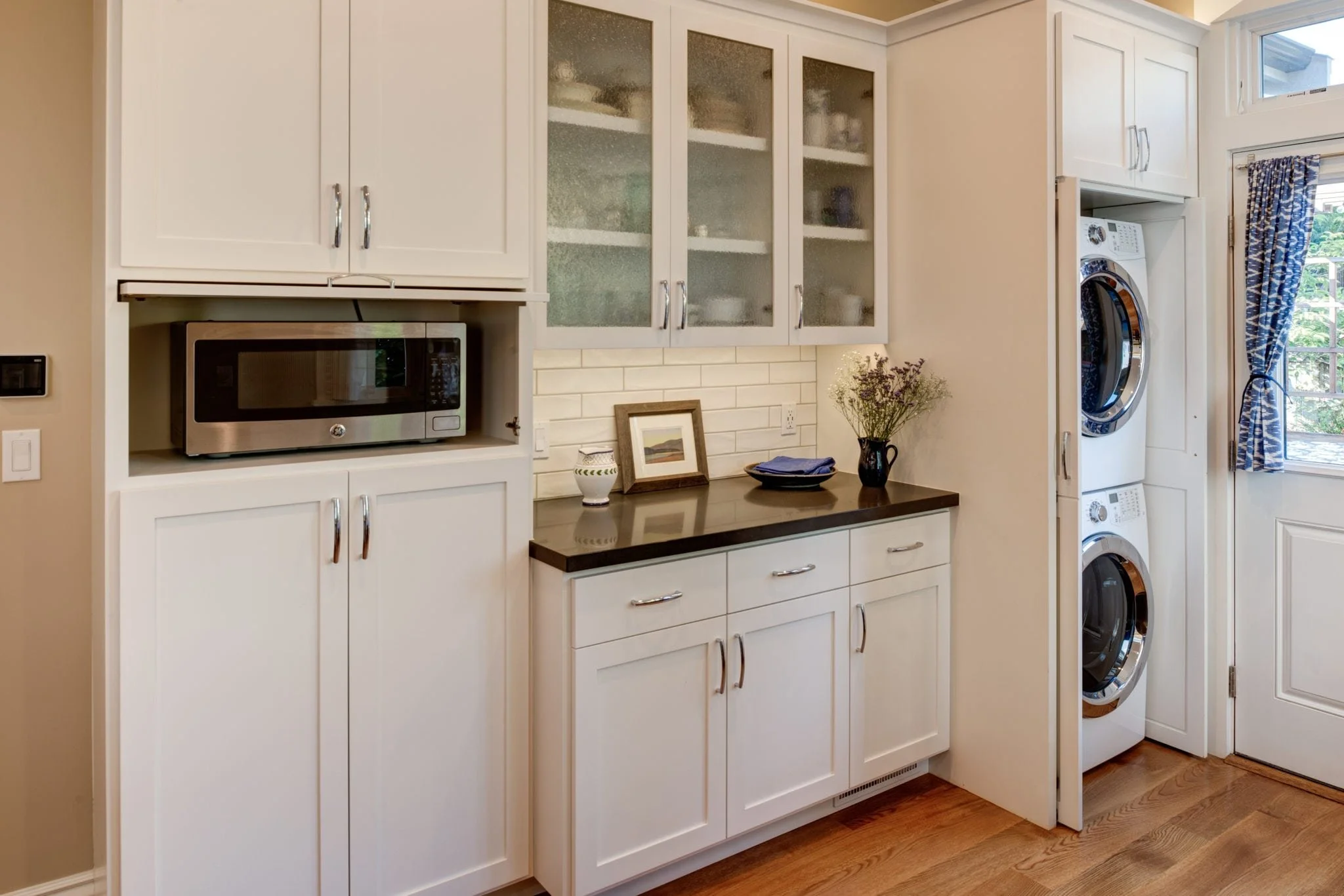 Stacked washer/dryer hidden behind cabinetry matching kitchen finishes