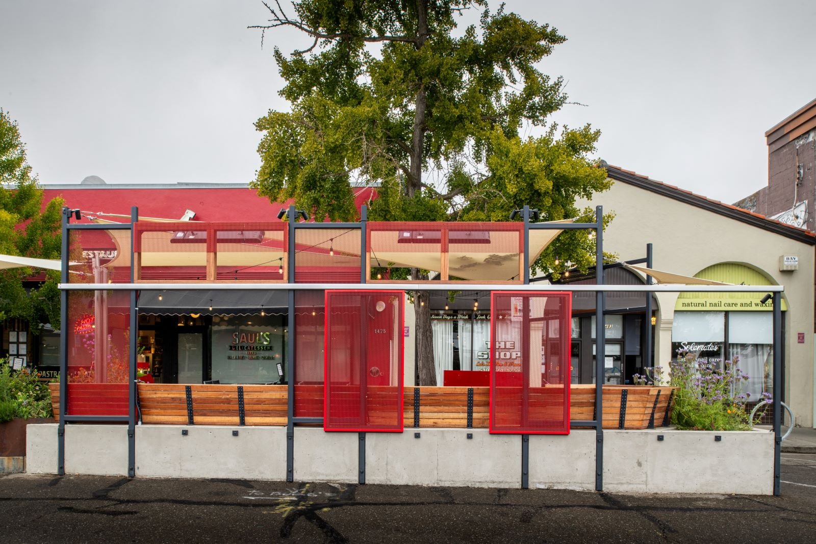 Full view of street side of the parklet capturing the perforated rectangular metal shades that slide along two sandwiched flat bars.