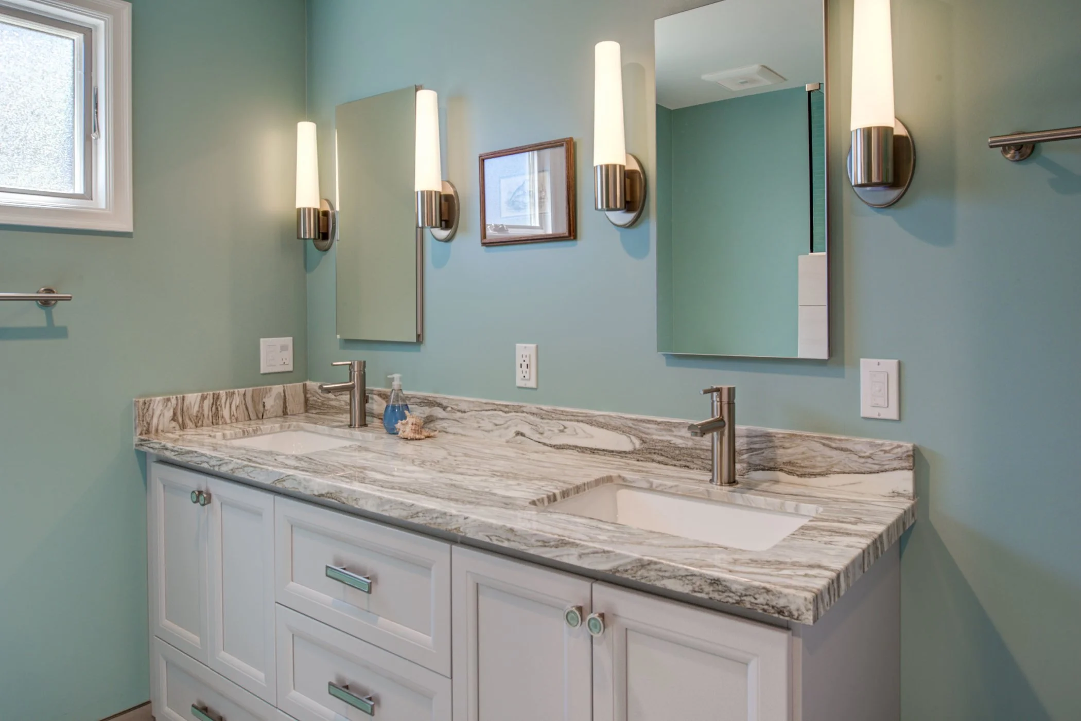 Double vanity in the primary bathroom with marble countertop, modern fixtures, soft blue walls, and integrated lighting for a clean and updated look.