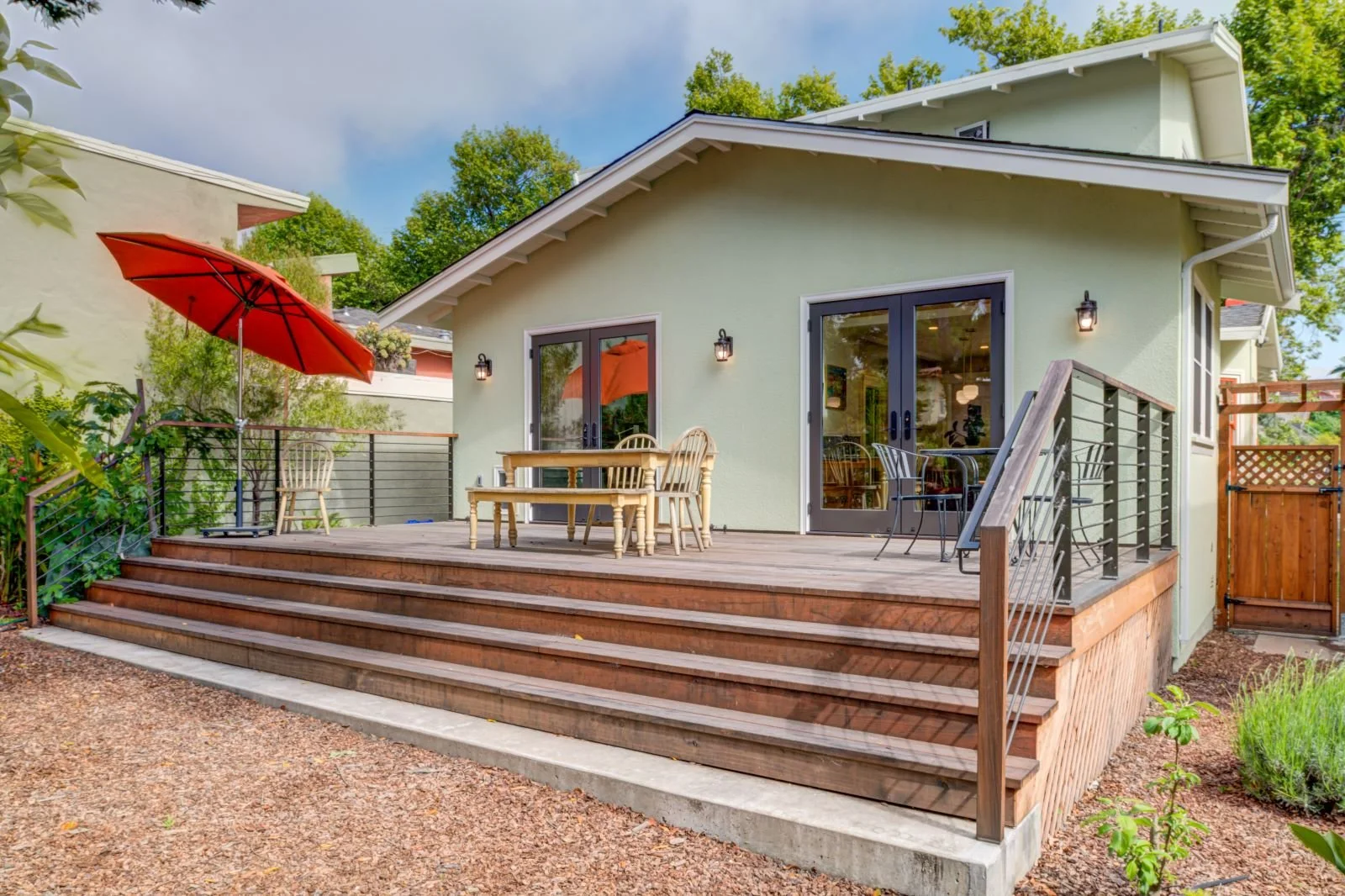 View of new rear deck with full-width stairs to the yard, accessed via French doors