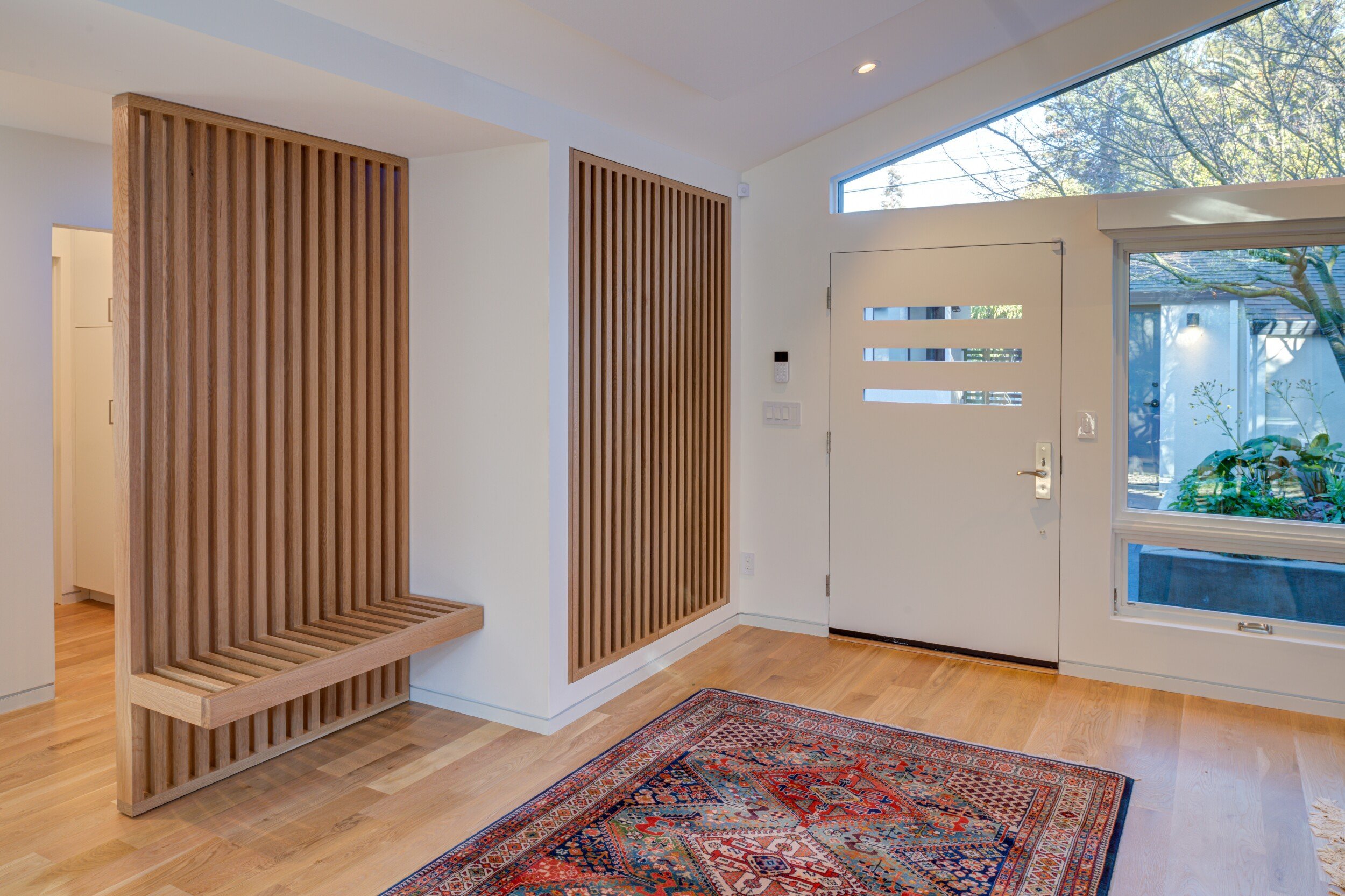 Custom entry bench/screen to the hallway with the coat closet disguised behind the same vertical wood elements