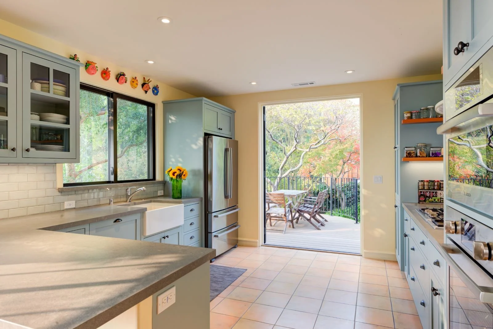 Full Kitchen shot with view through open French doors to the new Deck. Soft blue Shaker cabinets, white subway tile backsplash and tile floor are classic and durable.