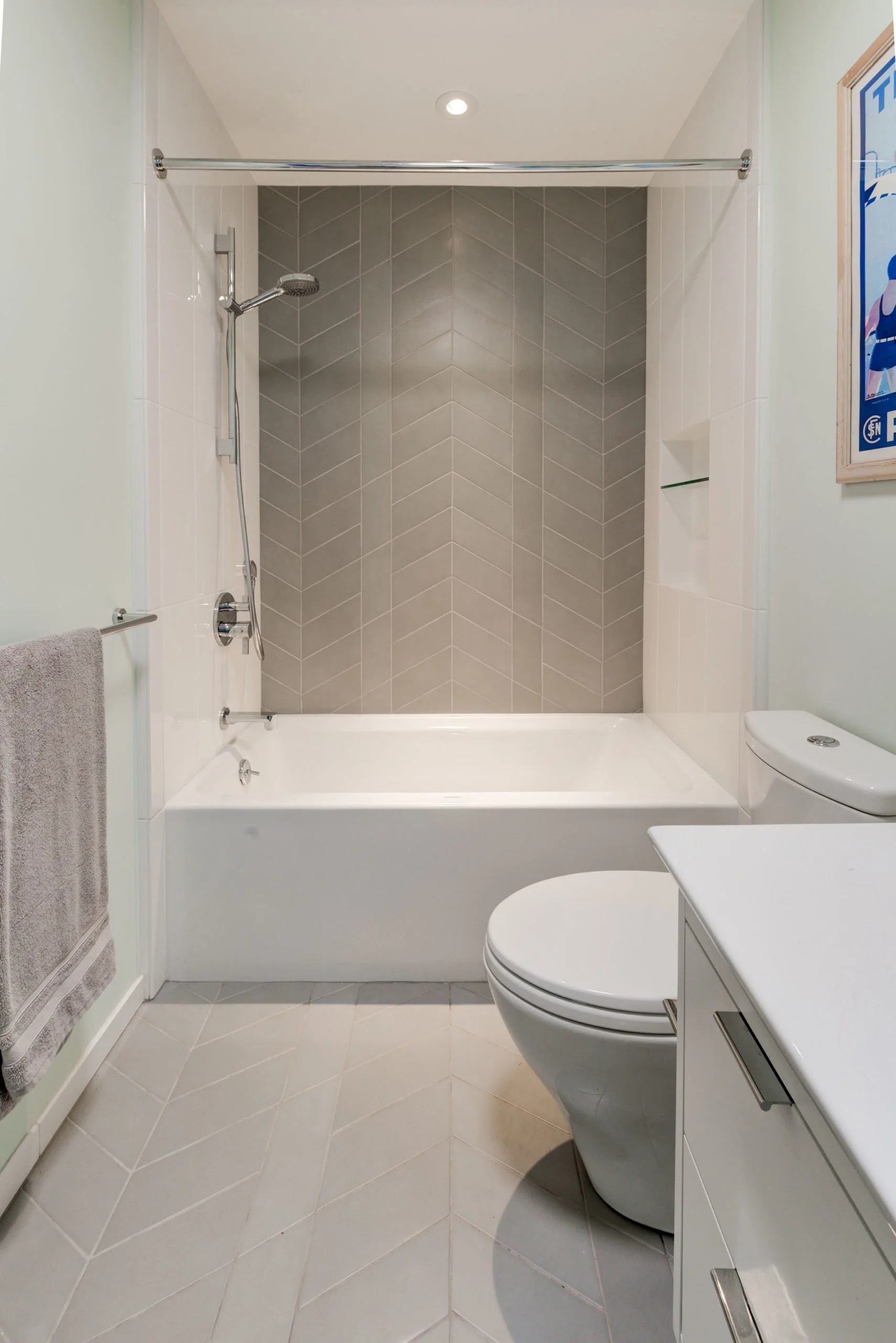 Secondary bathroom with a bathtub and shower, light walls, simple vanity, and patterned tile, continuing the home’s use of color and texture in a family-friendly way.