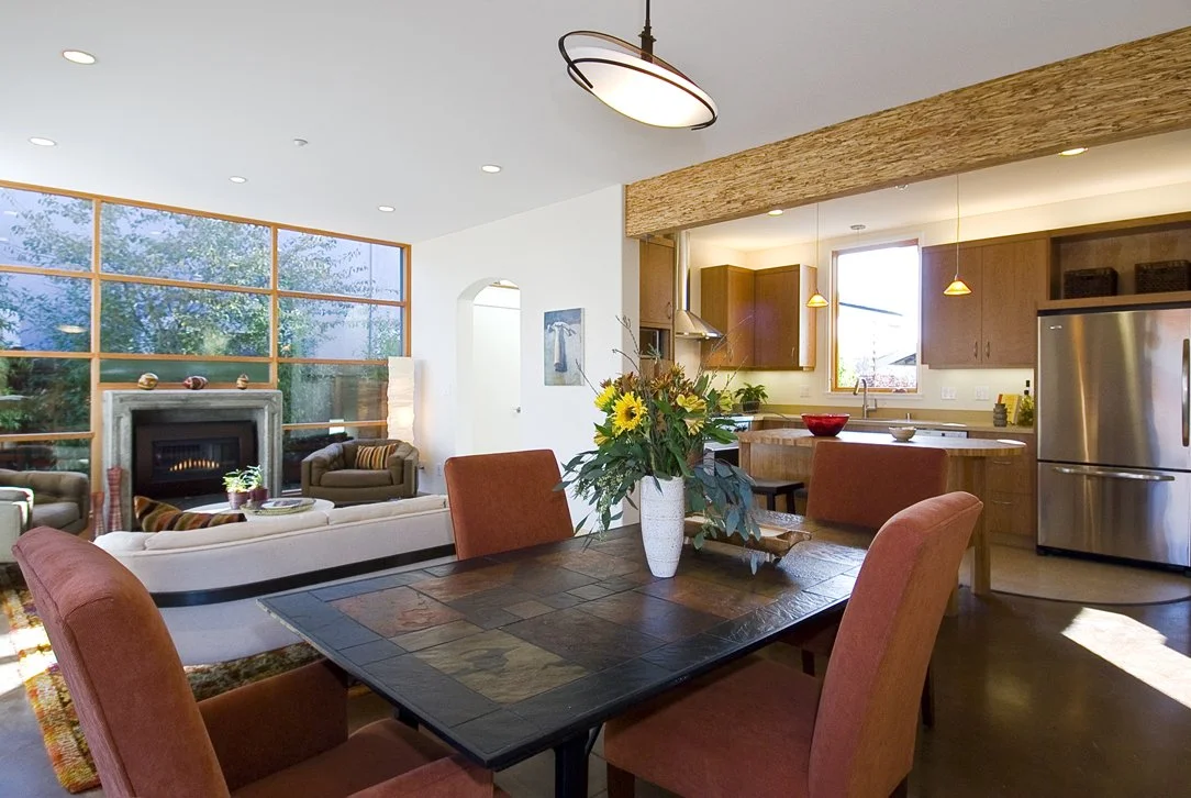 Dining area looking toward the kitchen and living room, showing integrated spaces, warm wood finishes, and daylight driven design that supports everyday family living.