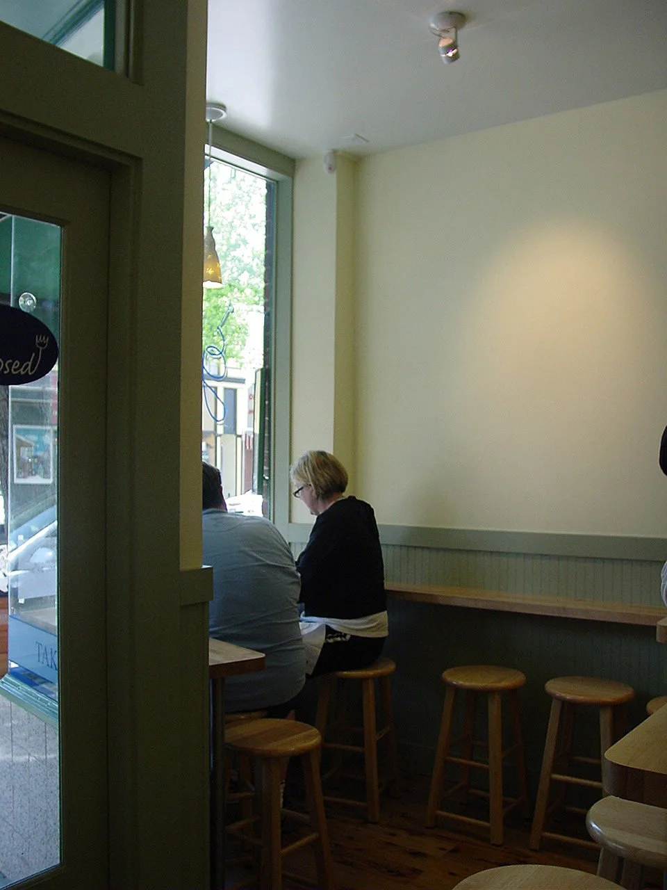 Dining area at Grégoire Piedmont with a wood counter, row of stools, and customers seated by the front window, showing the larger, more workable space created by Levitch.