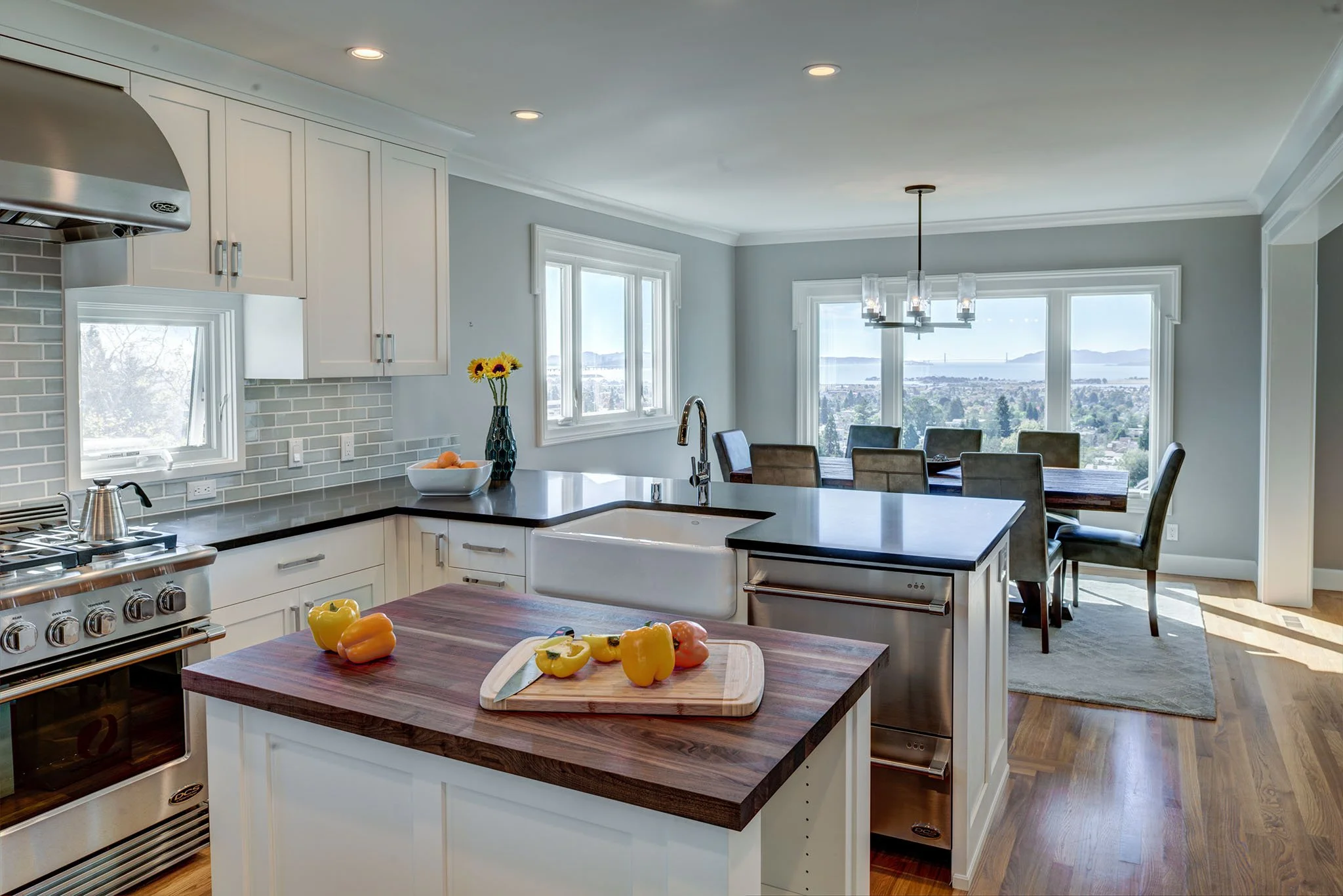 Open kitchen with a farmhouse sink and wide island that flows into the dining area. Large windows frame Bay views, creating an easy layout for entertaining on Berkeley game day weekends.