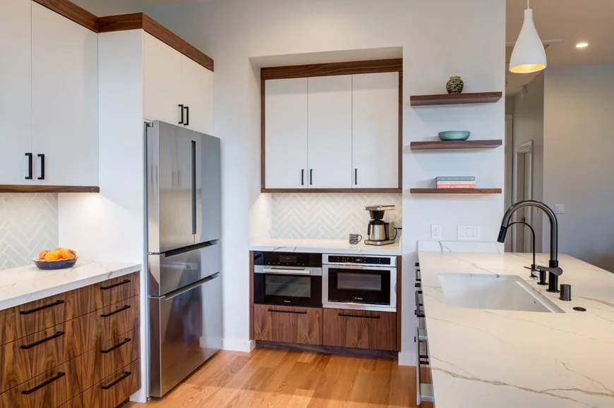 Kitchen detail showing integrated refrigerator, wall ovens, and custom walnut storage that maximizes function and supports the needs of a multigenerational household.