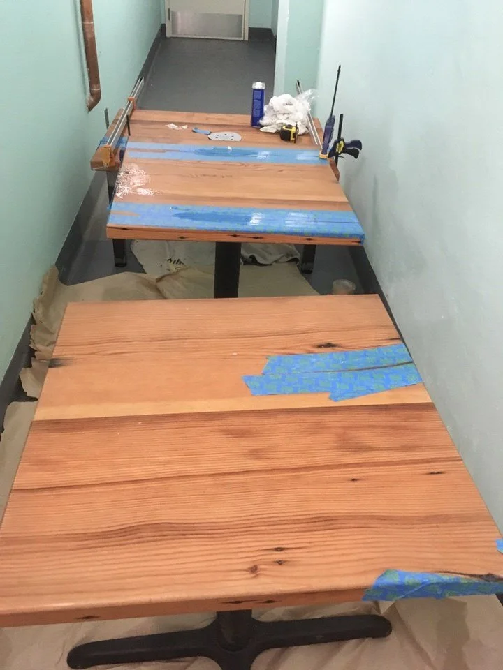 Custom solid wood tables under construction during the Arizmendi Bakery remodel, showing hand finished surfaces prepared for use in customer seating areas.