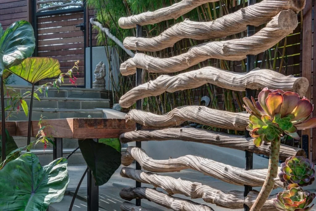 Custom railing made from branch like natural forms along the garden steps and terrace edge, softening the stone and wood outdoor living surfaces with an organic look.