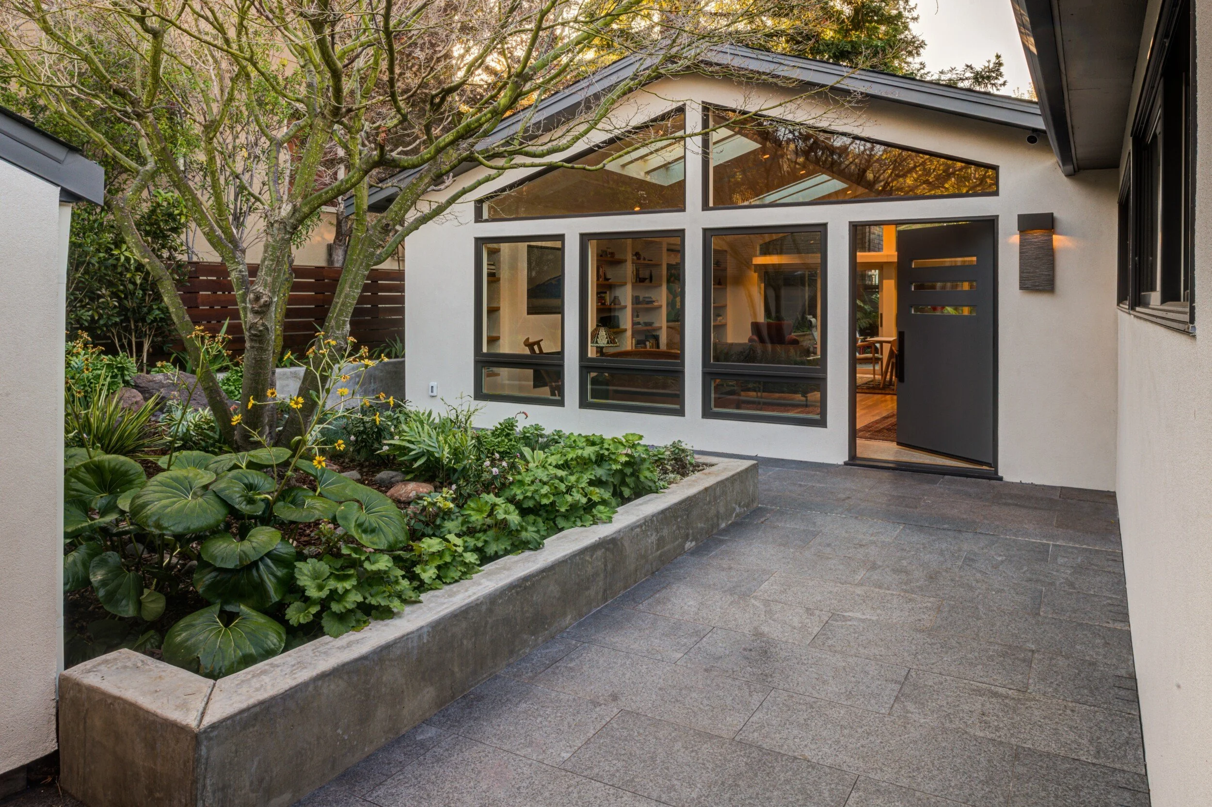 Courtyard approach to the front door, with a wall of new windows to take in the view and light