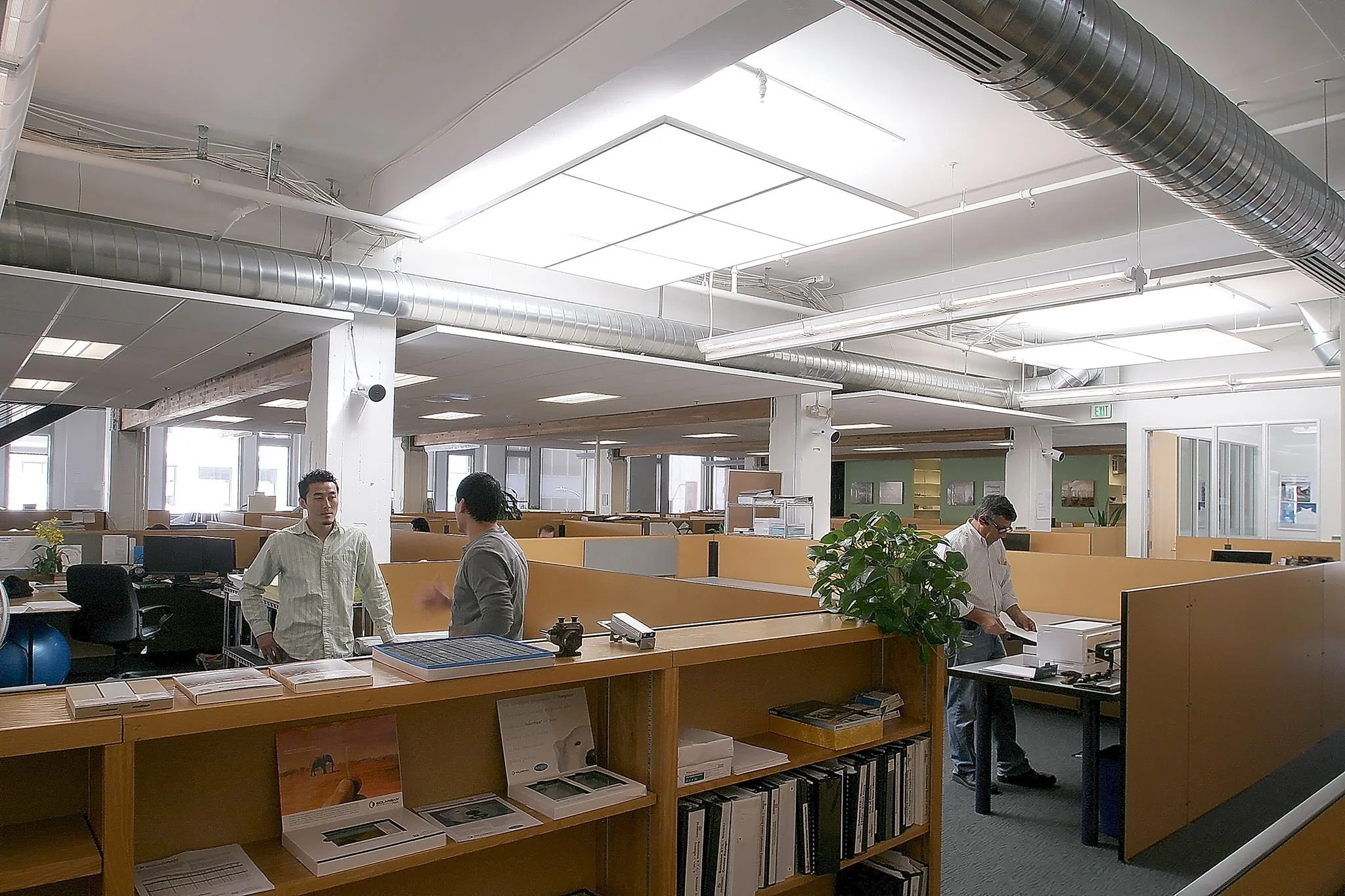 Open plan office with large ceiling light monitors, exposed ductwork, and efficient lighting for automatic dimming, creating bright workstations with reduced energy use.