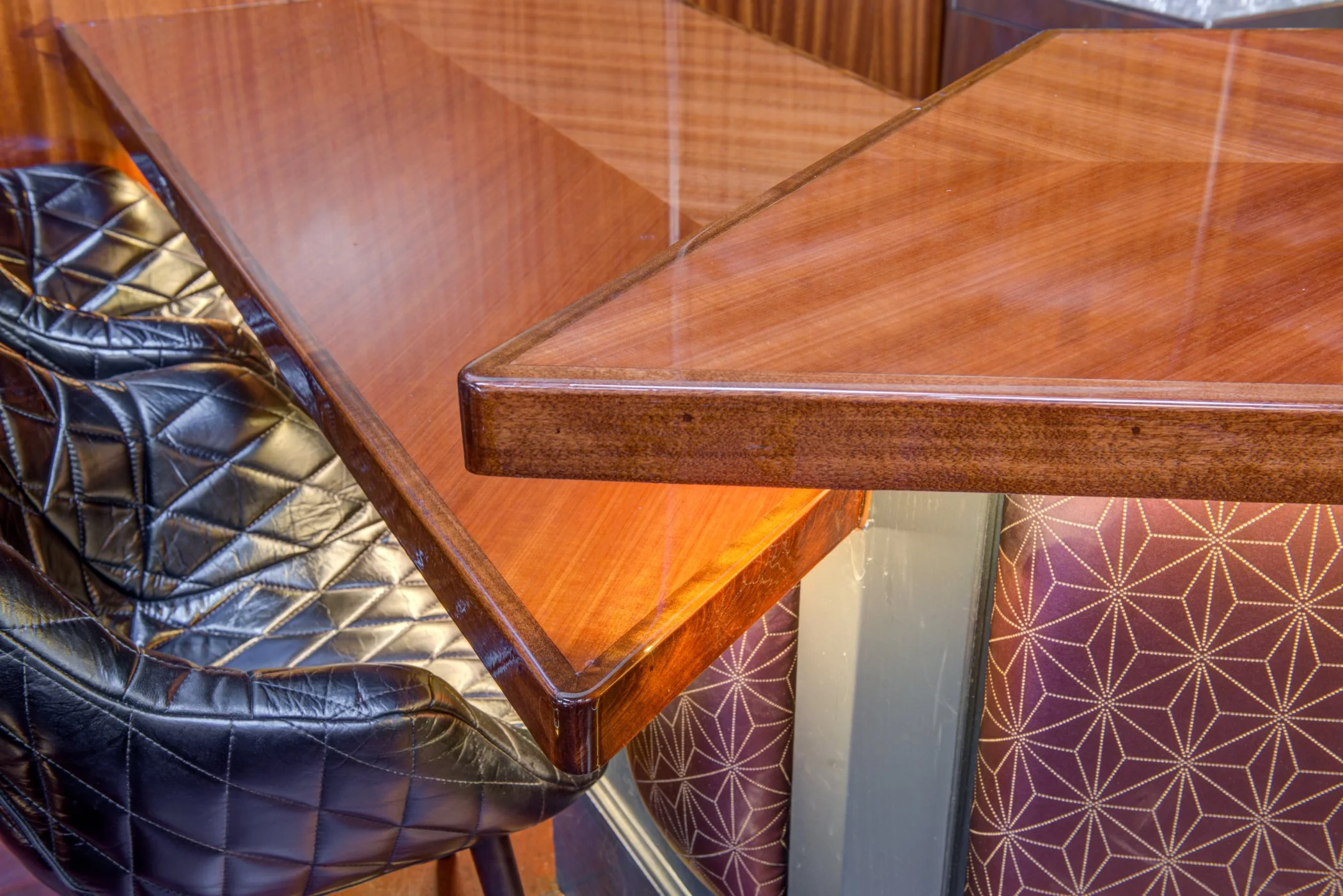Custom wood bar top detail with quilted leather seating at Bardo Lounge.