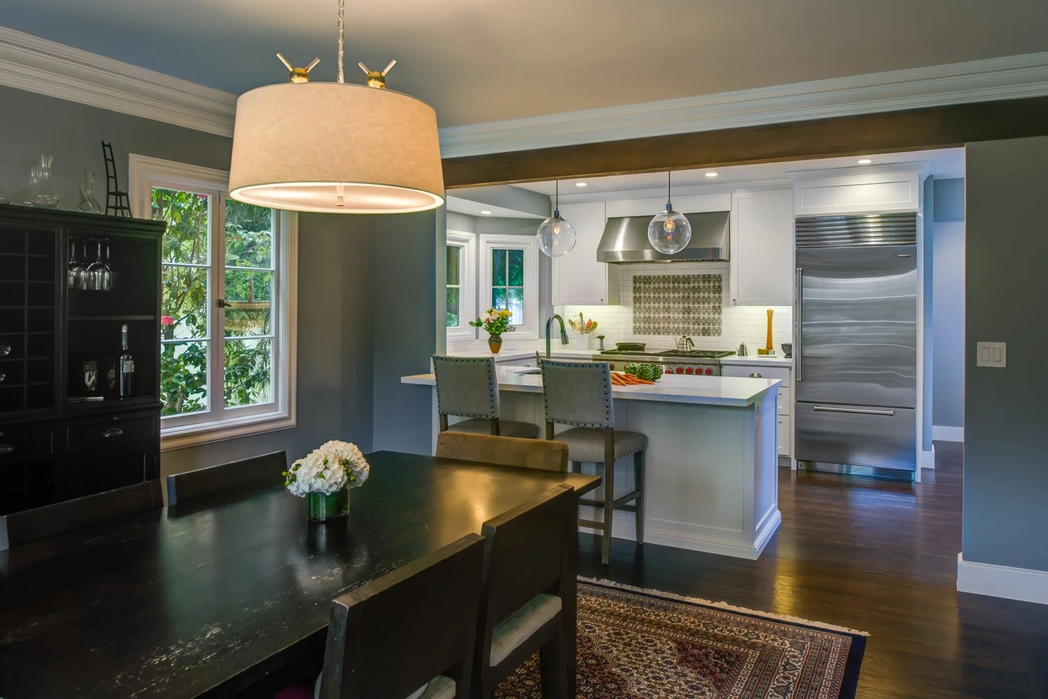 View from the dining room into the remodeled kitchen through a widened opening, showing a bright island workspace and improved flow while keeping each room distinct.