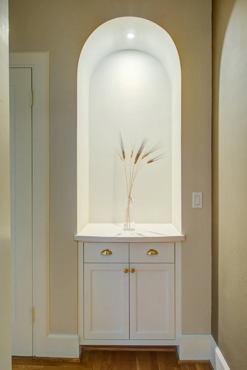 Built-in arched wall niche with soft accent lighting and a small display shelf, showing refined architectural detailing added during the bathroom remodel that borrowed space from surrounding areas.