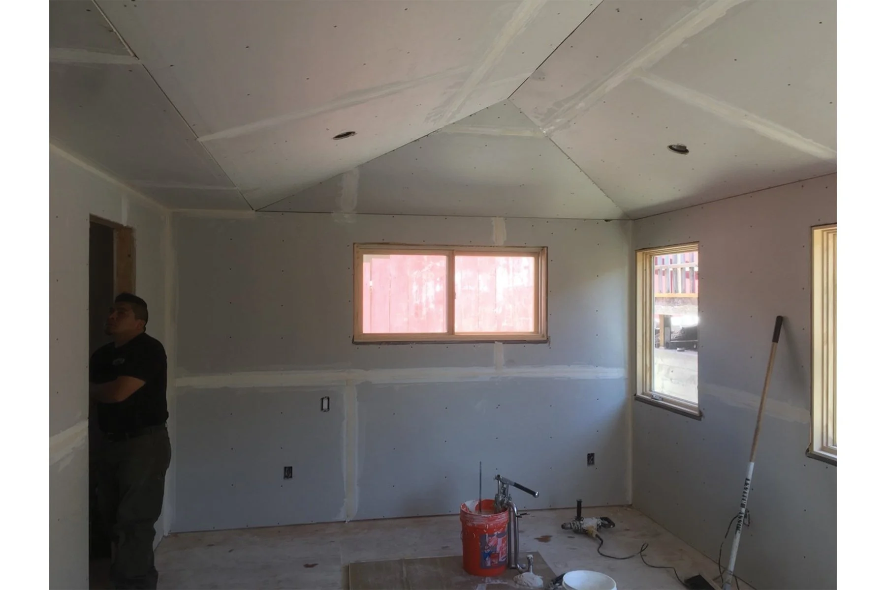 Bedroom addition under construction with new drywall, vaulted ceiling shape, and window openings, showing progress as Levitch builds the 316 square foot primary suite addition.