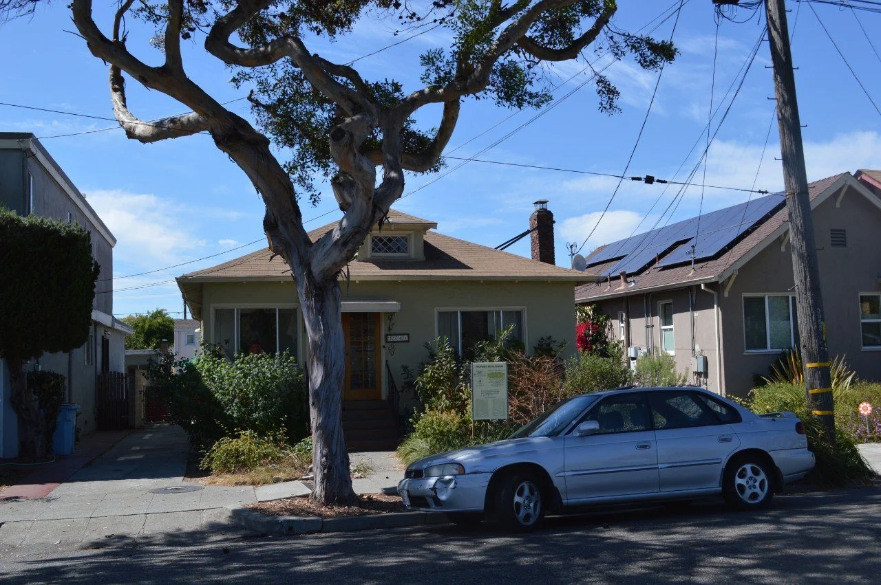 Street view of the bungalow before the remodel, showing the original single story form, small porch, and street tree canopy before Levitch expanded the back.
