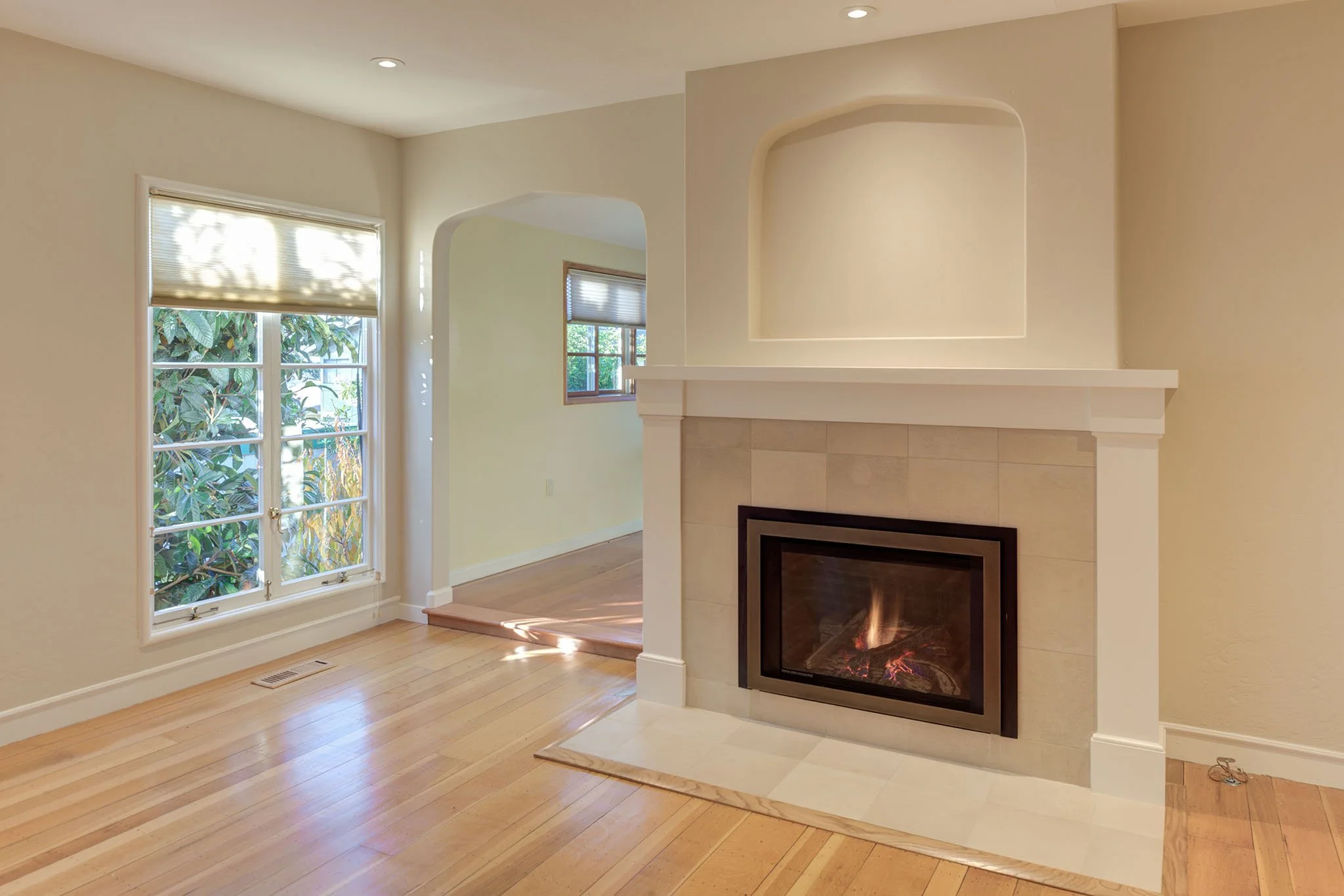 Levitch living room update with widened opening and a modern gas fireplace insert, new tiled surround, white mantel, and display niche, bringing a clean classic look.