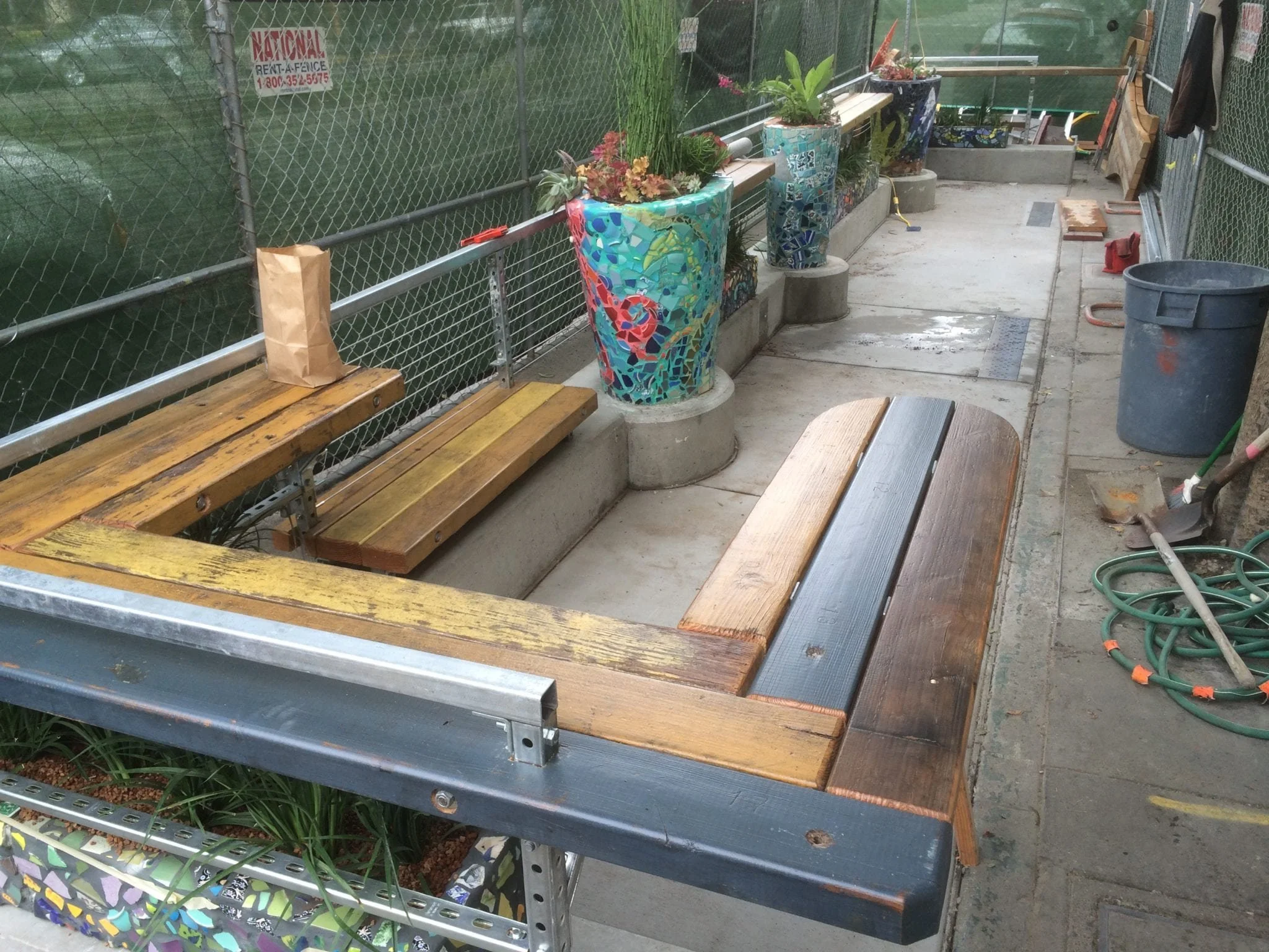 Detail of mosaic planter in progress with tile fragments being applied around large planter vessel