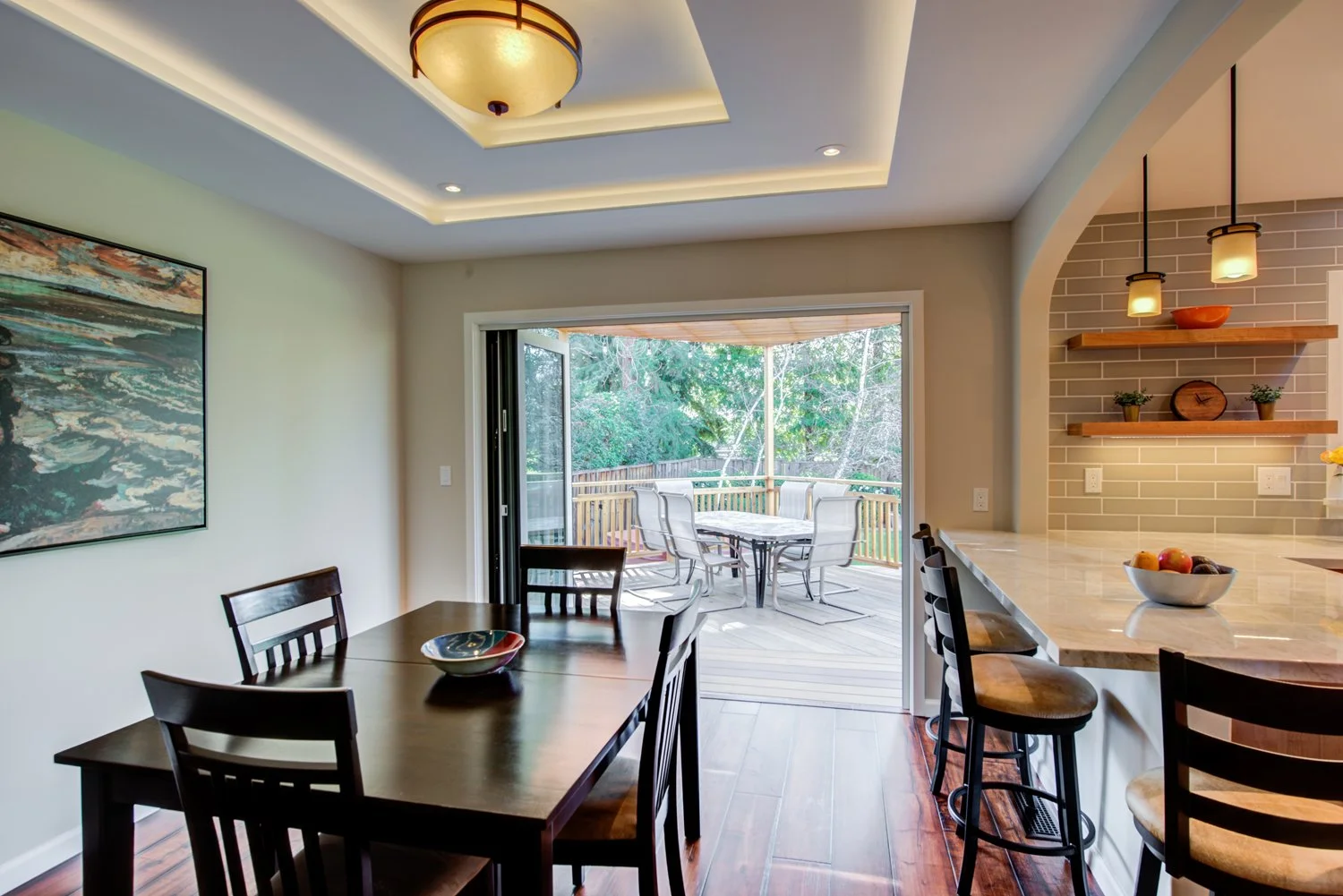 Dining room with open doors to outdoor deck, showcasing seamless indoor-outdoor flow.
