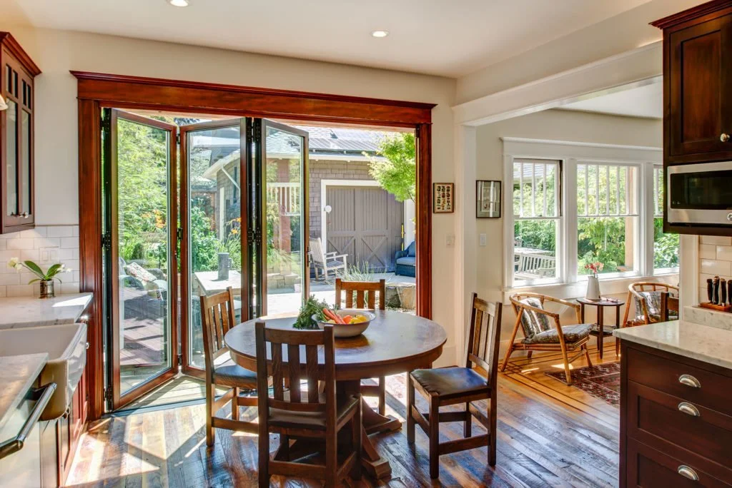 Angle view of the folding doors as they open from the kitchen to the patio deck, highlighting the modern door system set within a Craftsman remodel on sunny days.