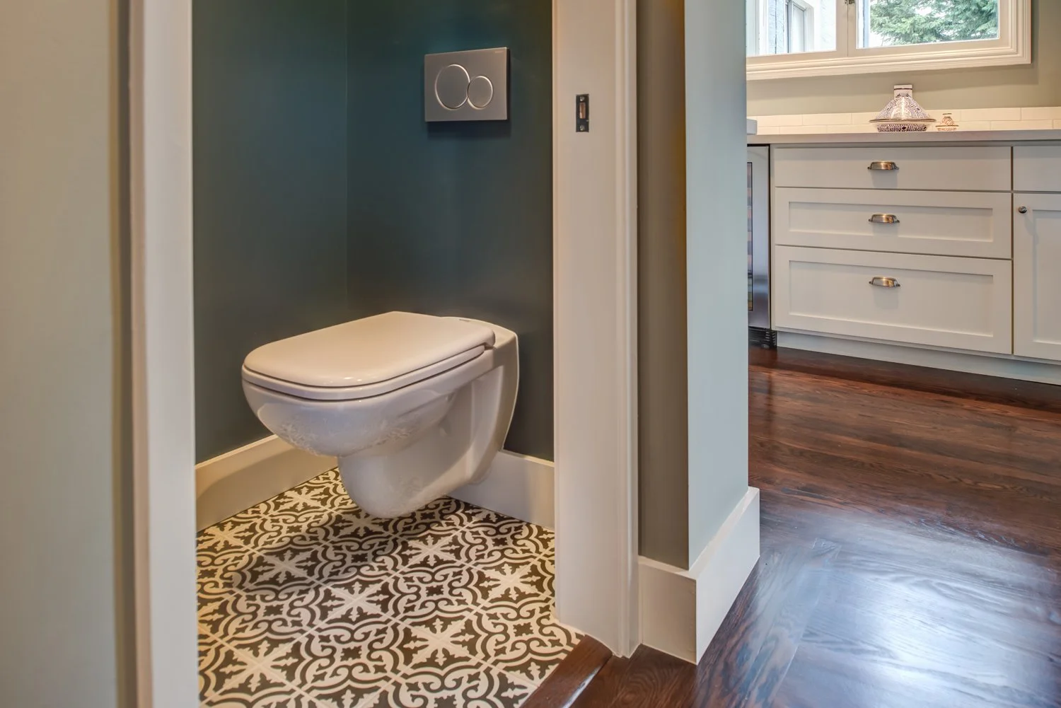 New first floor powder room with patterned floor tile and a wall mounted toilet, added by Levitch to improve function and convenience near the main living areas.