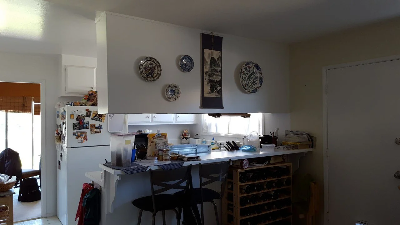 Original kitchen and dining connection showing a compact peninsula, low ceiling opening, and visual separation prior to reconfiguration for a more open plan.