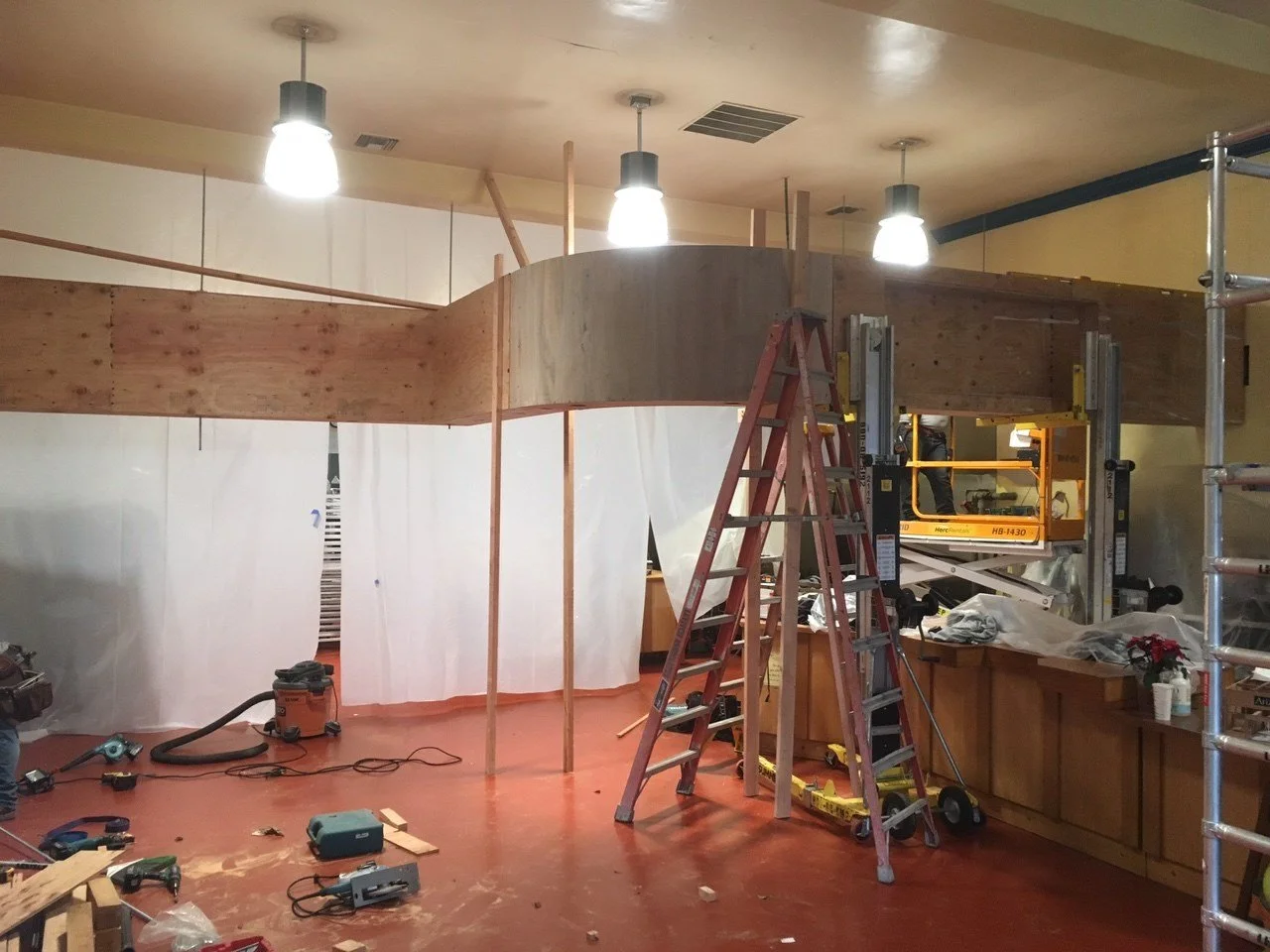 Curved soffit under construction above the service counter at Arizmendi Bakery, framing the customer area and concealing mechanical systems during the remodel process.