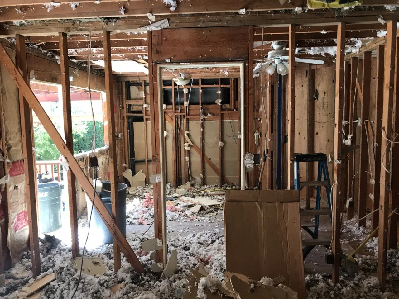 Kitchen demolition phase with cabinets removed and walls open to studs, preparing for structural updates and new design layout.