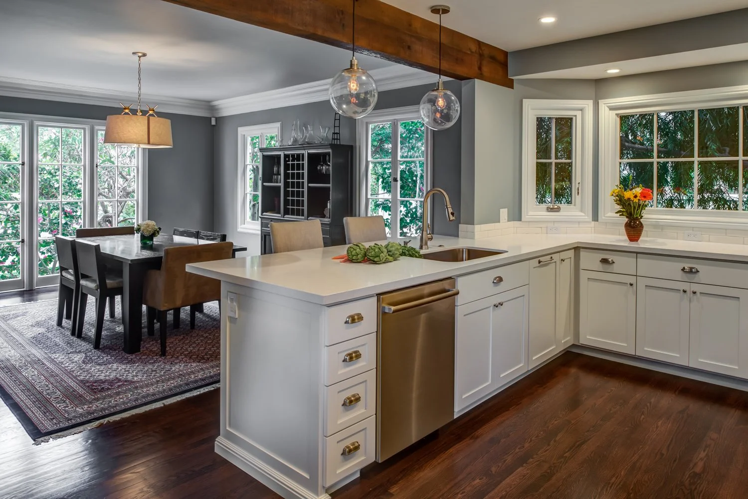View from the kitchen toward the dining room showing the new opening, island sink, and clear circulation path that improves entertaining while preserving distinct rooms.