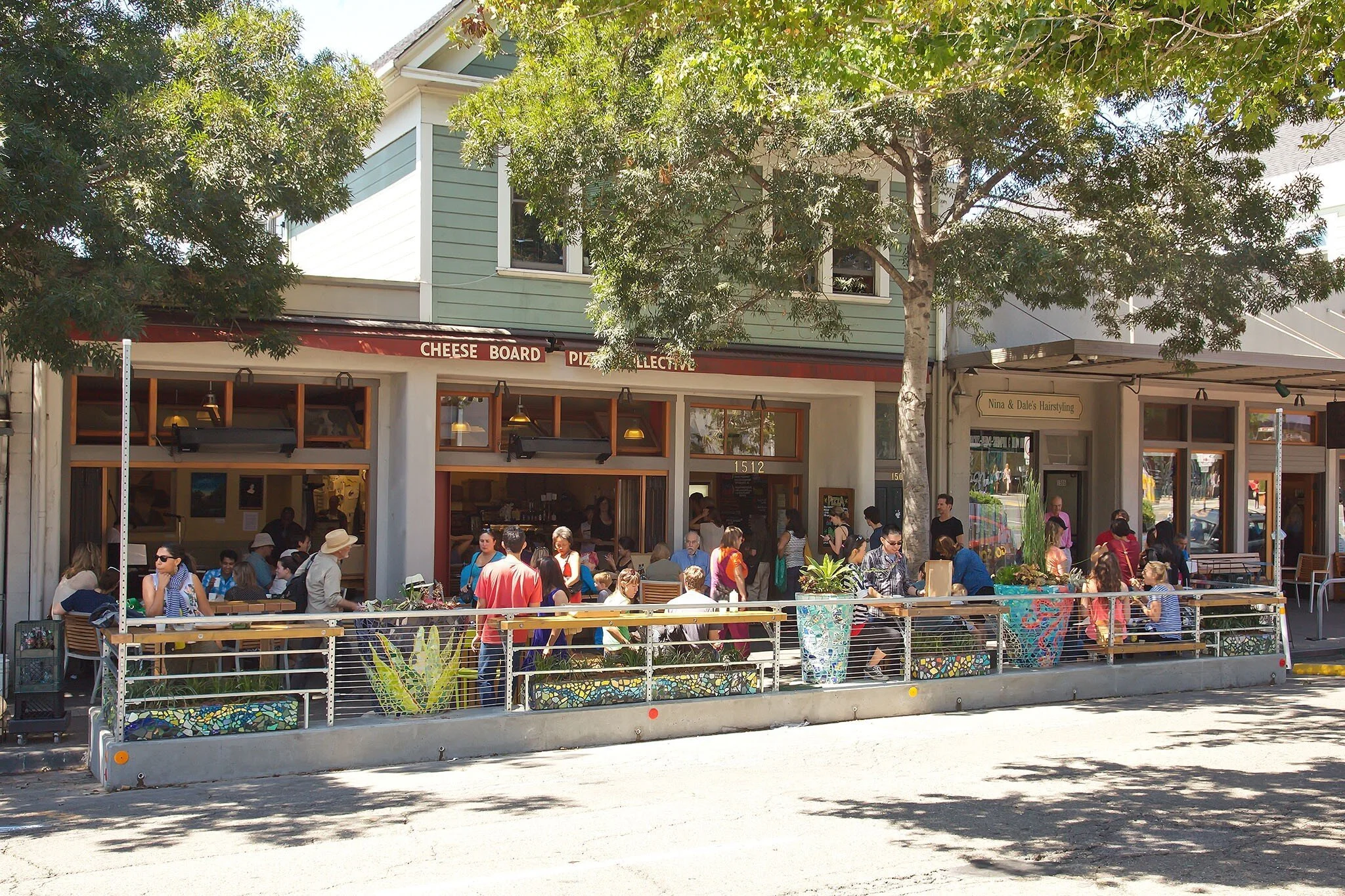 Front view of Cheese Board Pizza Collective parklet showing café storefront and public sidewalk seating