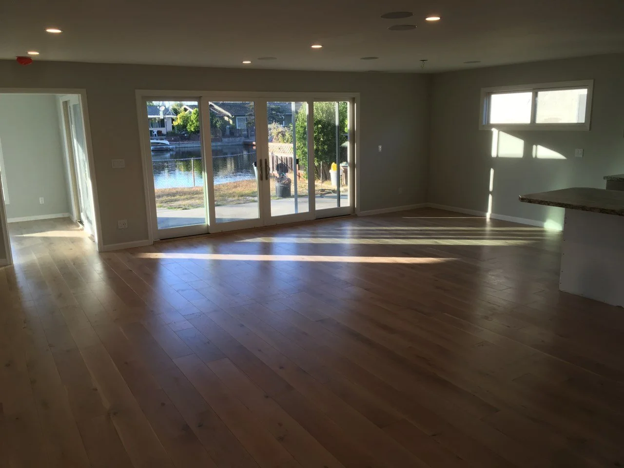 Finished open living area with sliding glass doors opening to the waterfront, showcasing improved flow, light, and connection to outdoor spaces.