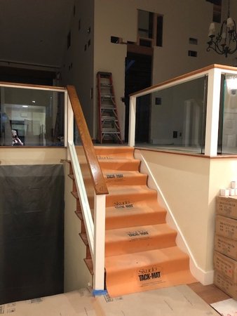 Staircase during construction with temporary treads and railings installed, documenting progress toward the new glass and metal stair system.