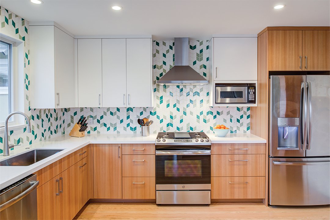 Updated kitchen with Levitch built eucalyptus base cabinets, white uppers, stainless range and hood, and green Fireclay Tile backsplash over white counters in a midcentury home.