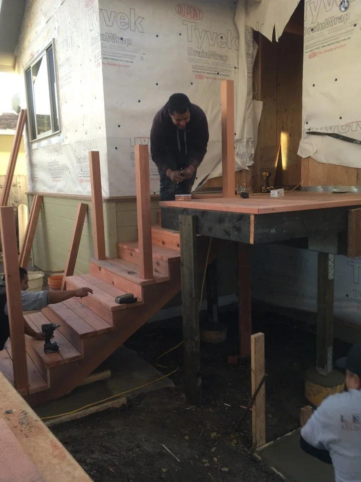 Construction team installing new exterior stairs and landing framing to accommodate lift addition and improved rear-entry access.