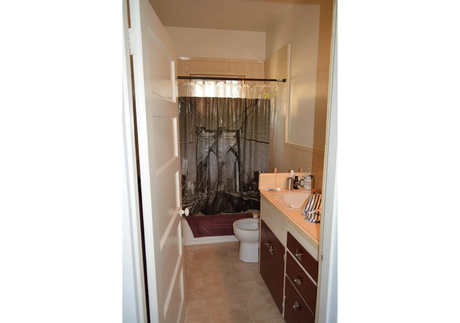 Original bathroom layout before remodel, featuring dated vanity, tile surround, and tub area planned for accessibility-focused upgrades.