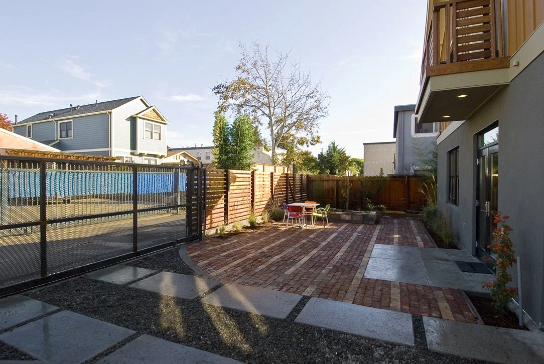Rear parking and outdoor patio area paved with recycled brick, featuring low maintenance landscaping and durable materials that support sustainable site planning and everyday functionality.