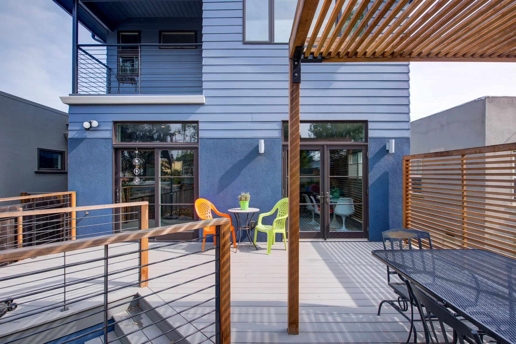 Backyard deck with pergola and cable railing, set against the new addition. Glass doors open to the kitchen and dining area, creating easy indoor outdoor living and shade.