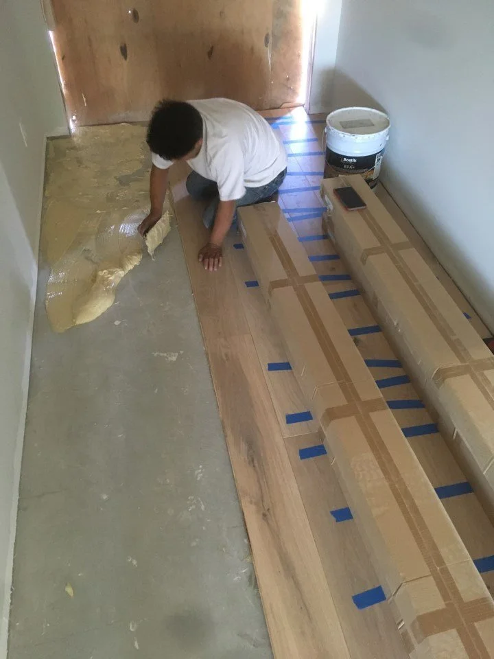 Installation of wide plank wood flooring during the Alameda remodel as part of the transition from construction to finished living spaces.
