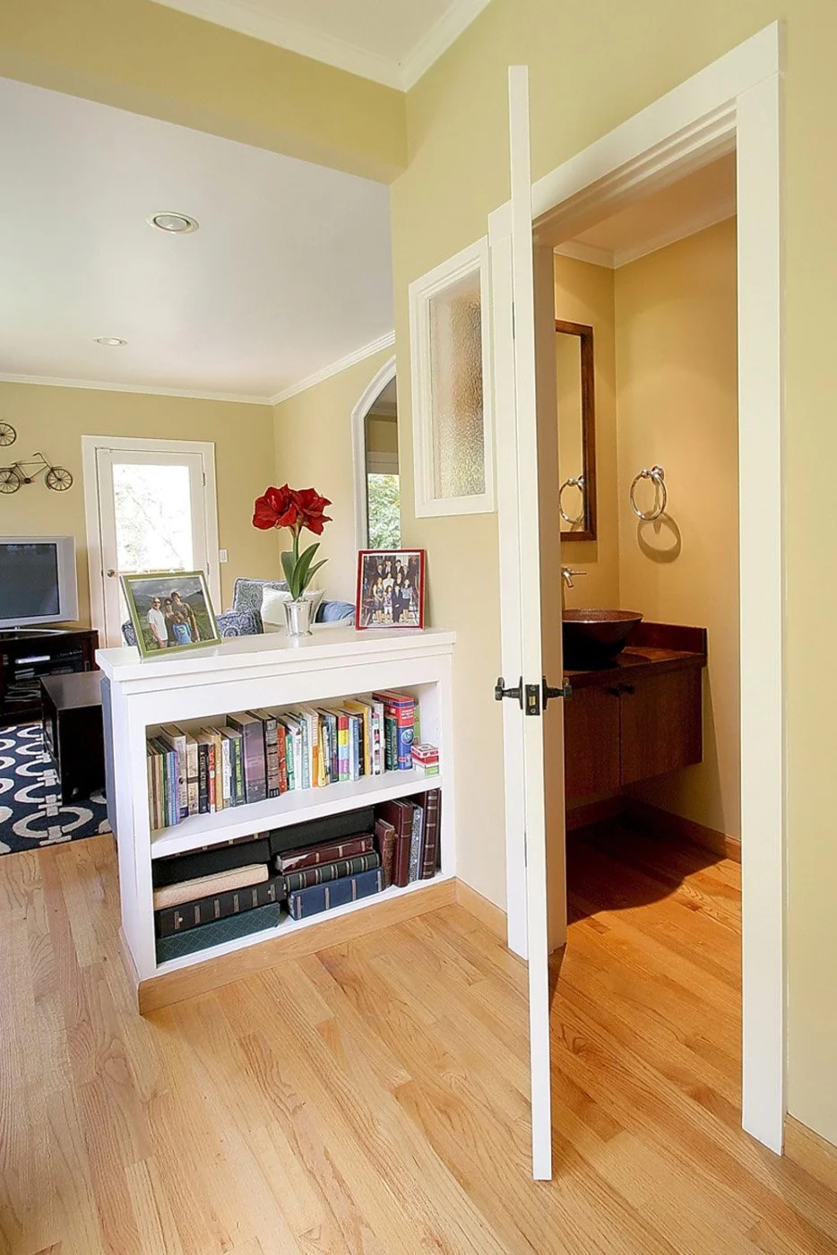 Small powder room entry off the living area featuring custom built-in shelving and warm wall colors.