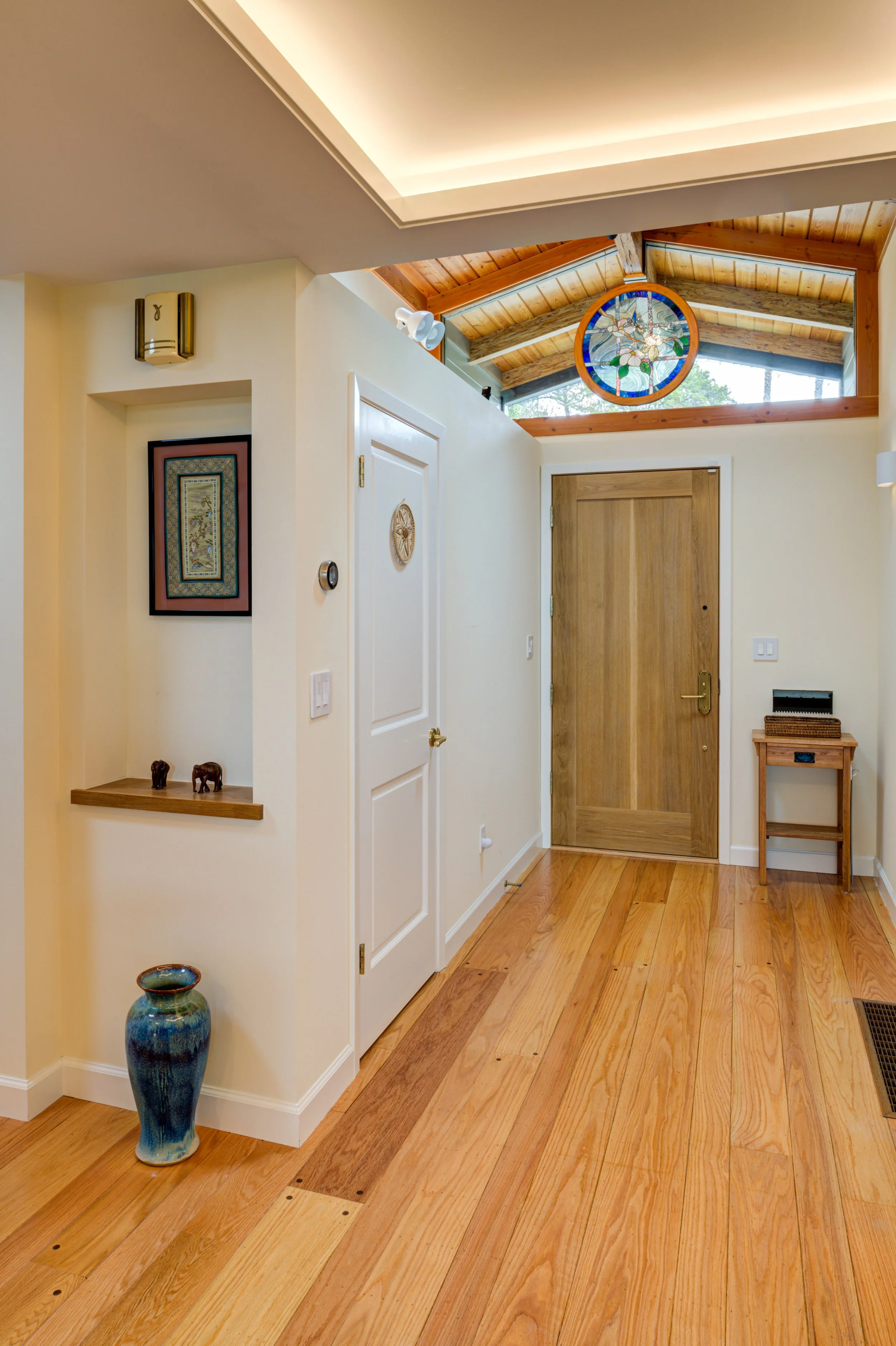 Entry hall from interior with transom over front door, custom stained glass, lit tray ceiling and wide plank flooring
