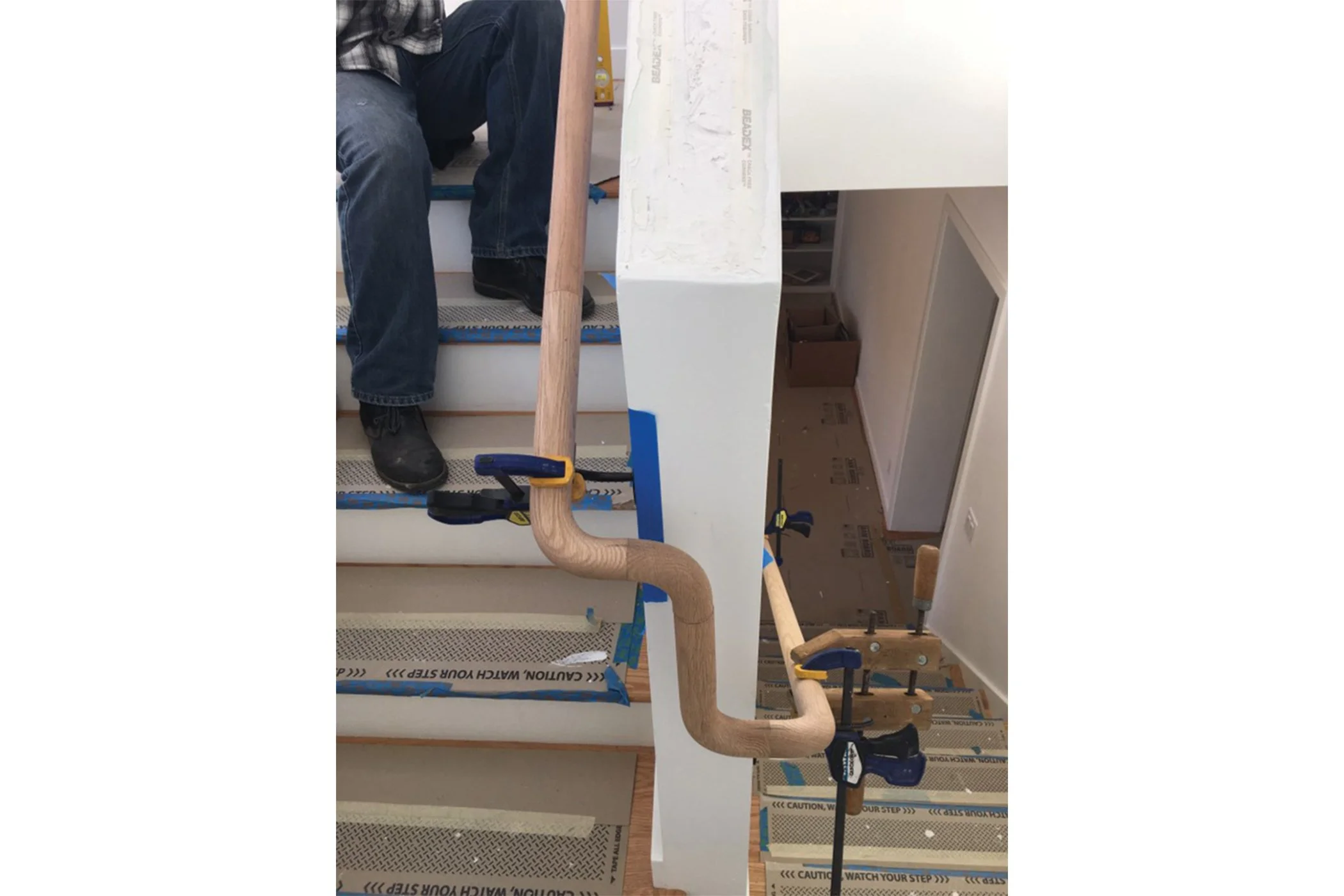 Wood handrail being clamped and installed along stairway under construction