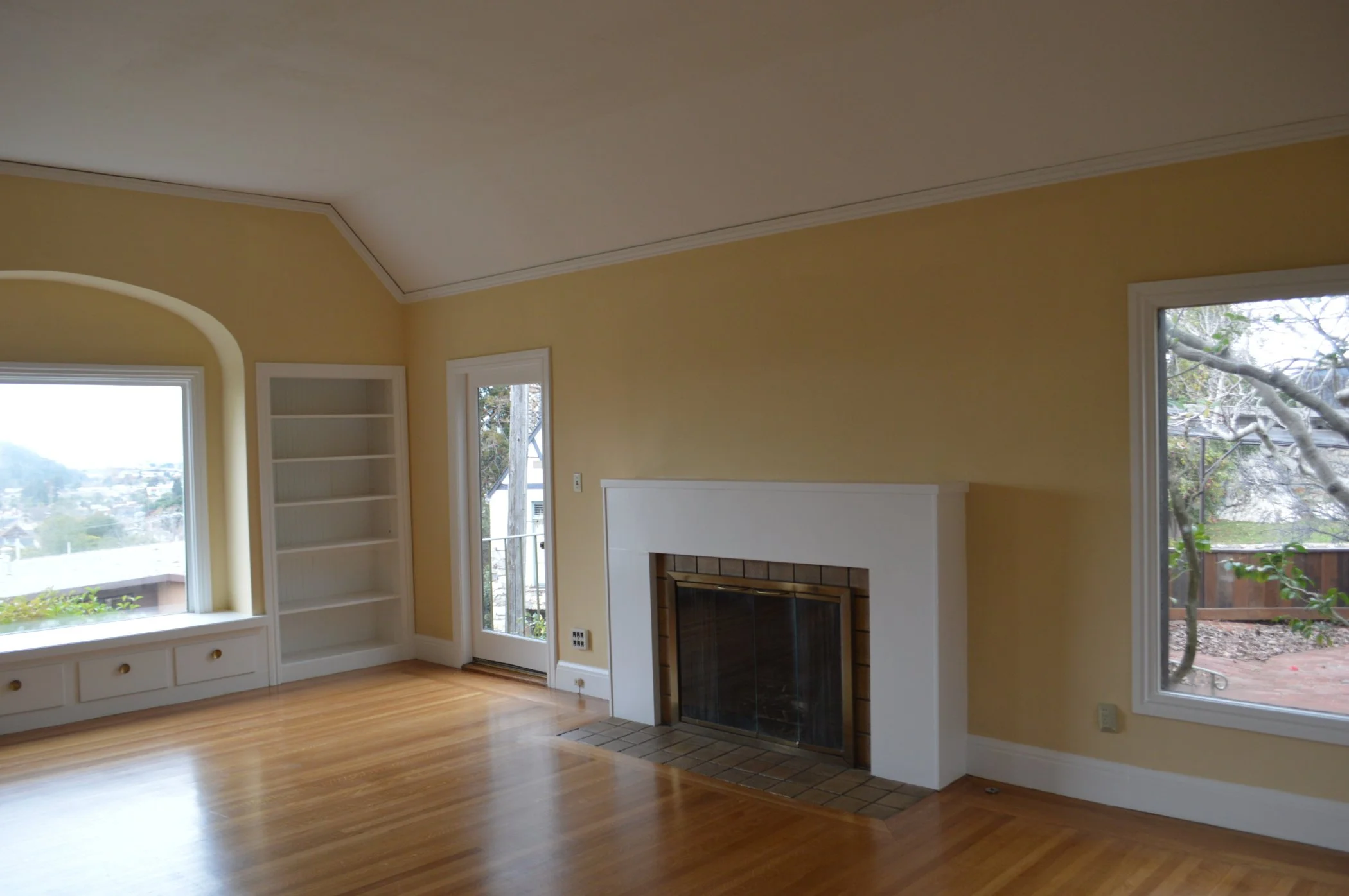 Living room before renovation, showing the original fireplace and chimney, older finishes, and empty floor area prior to adding the new gas fireplace and updated layout.