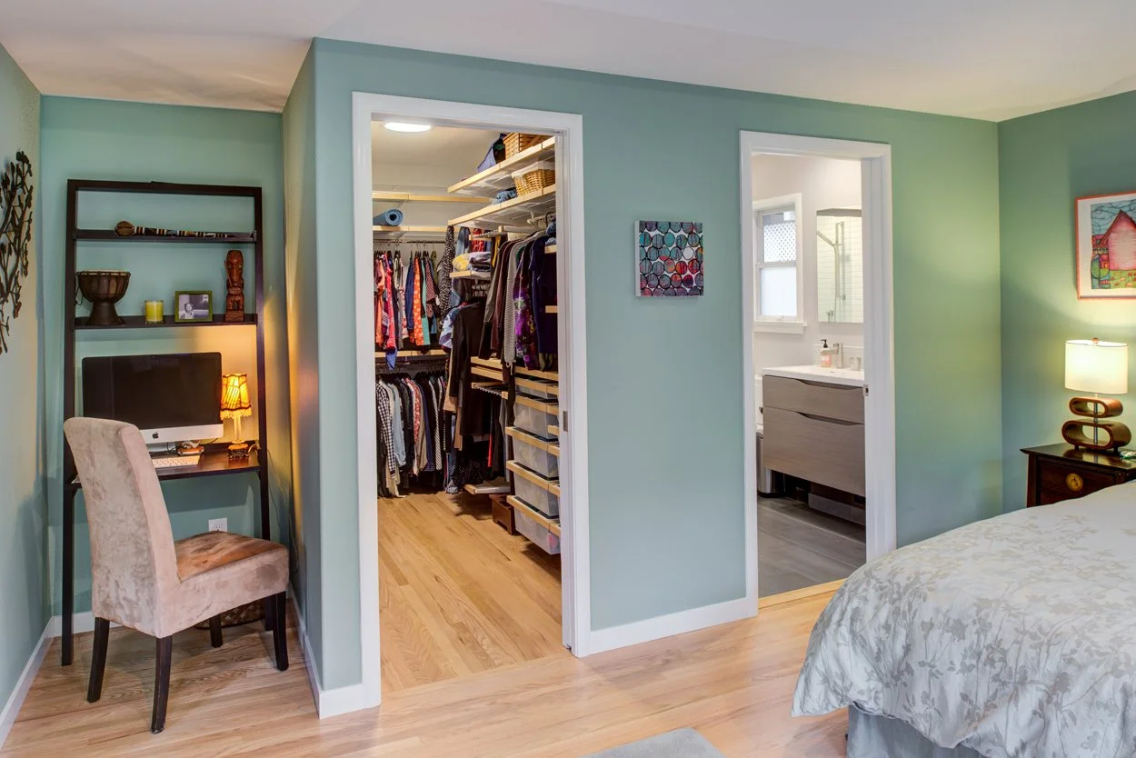 Primary bedroom corner with a small desk nook, plus doorways to the new walk-in closet and primary bathroom, part of Levitch’s 316 square foot bedroom suite addition.