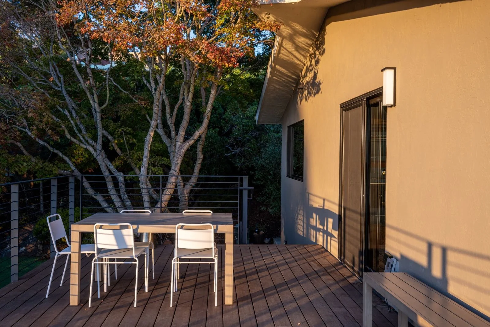 An intimate dining terrace nestles into the surrounding trees, pairing simple outdoor furnishings with filtered sunlight and a strong connection to the natural landscape.