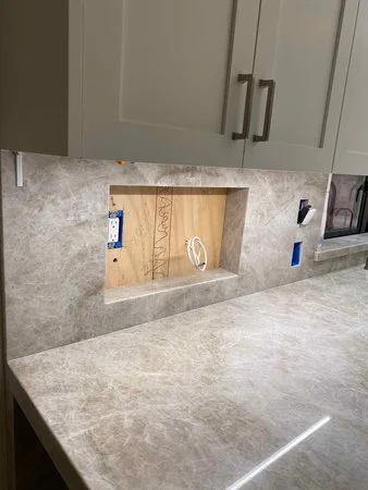 Kitchen backsplash niche under construction with wiring visible, prepared for a built-in television set flush into the stone backsplash.