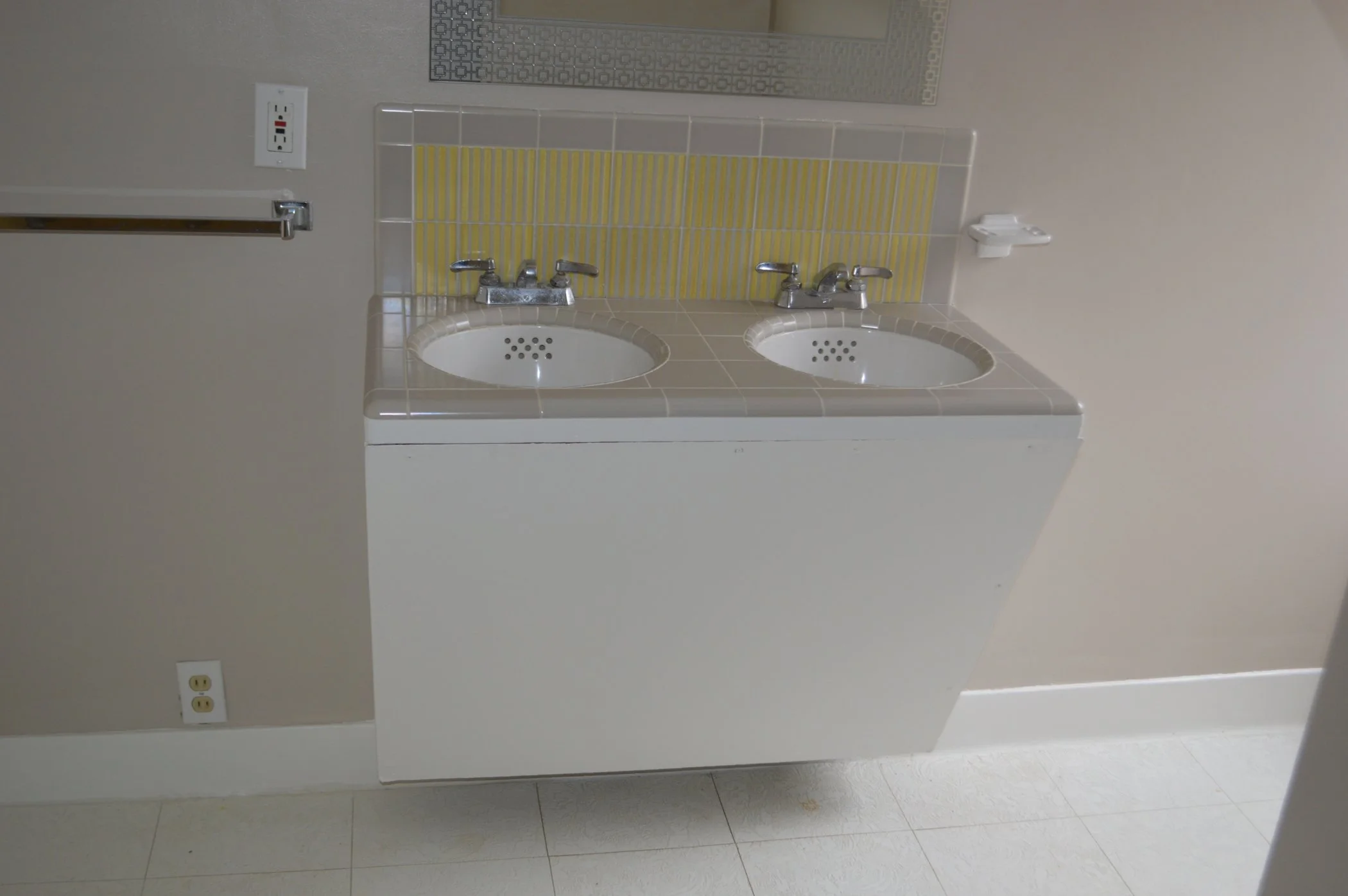 Bathroom before remodel with a dated double sink vanity, older tile countertop and backsplash, and basic fixtures prior to Levitch reconfiguring the space for better function.