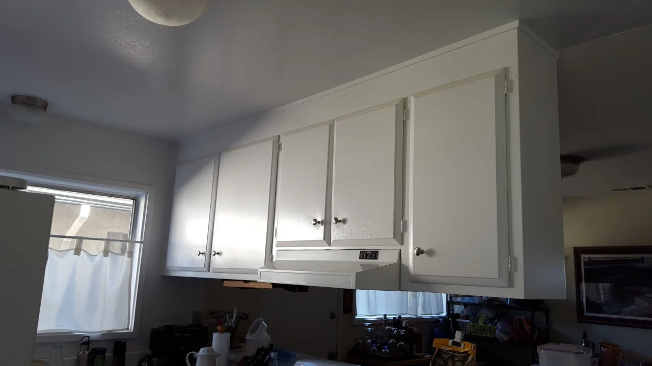 Existing kitchen upper cabinets with basic white doors, limited storage, and dated lighting before the Alameda remodel expanded and modernized the kitchen.