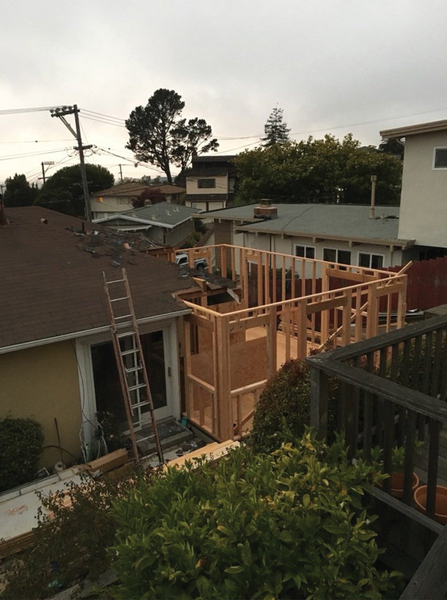 Exterior view of the new bedroom suite addition framed at the back corner of the home, with wall studs and roofline visible before finishes were installed.